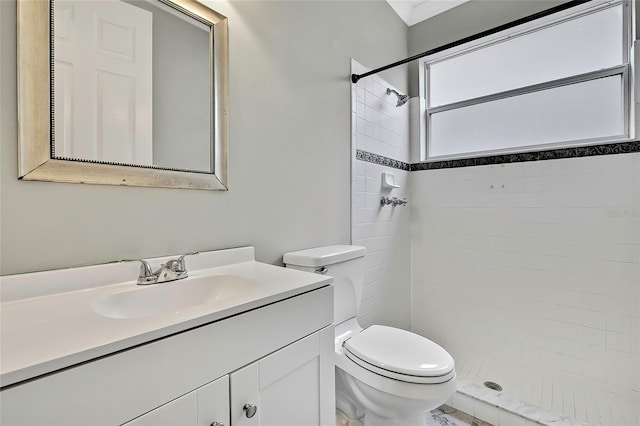 bathroom featuring a tile shower, toilet, and vanity