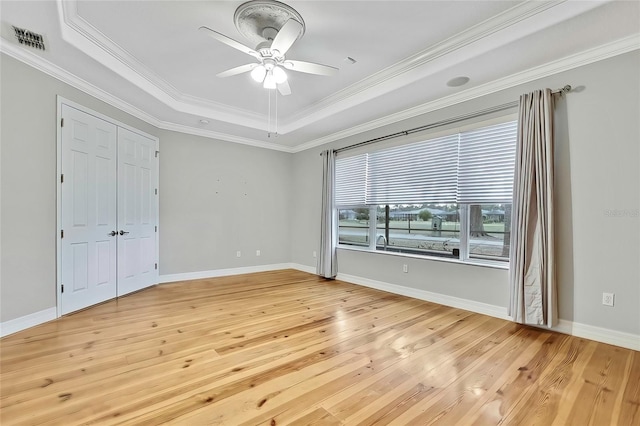 unfurnished bedroom featuring ceiling fan, light hardwood / wood-style flooring, a tray ceiling, and ornamental molding