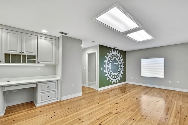 unfurnished office with light hardwood / wood-style flooring and built in desk