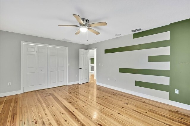unfurnished bedroom featuring light wood-type flooring, ceiling fan, and a closet