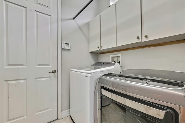 washroom with cabinets and washing machine and clothes dryer