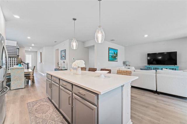 kitchen featuring light wood-type flooring, a center island, gray cabinets, and pendant lighting