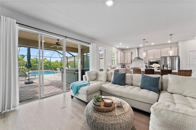 living room with light wood-type flooring, sink, and a textured ceiling