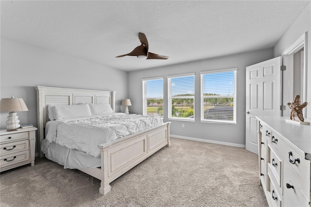 bedroom featuring a textured ceiling, ceiling fan, and light colored carpet