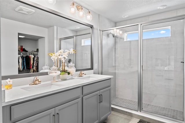 bathroom featuring a shower with shower door, vanity, tile patterned floors, and a wealth of natural light