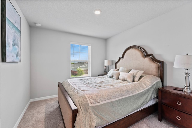 bedroom with a textured ceiling and light carpet