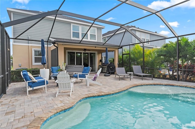 view of pool with ceiling fan, glass enclosure, a hot tub, and a patio