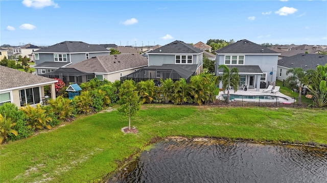 rear view of property featuring glass enclosure, a lawn, a patio area, a fenced in pool, and a water view