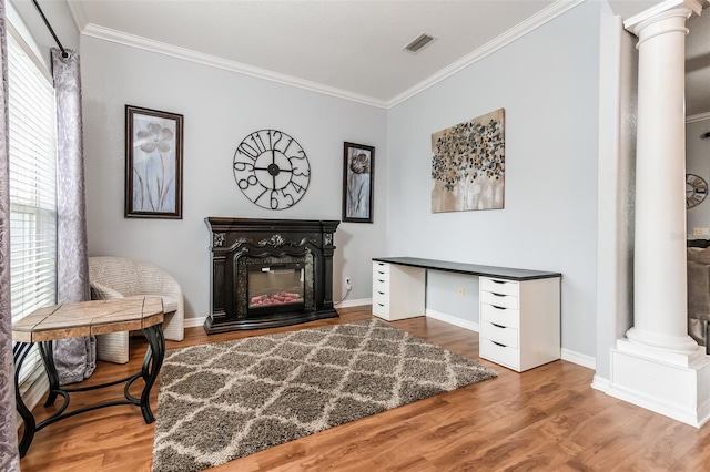 living area featuring decorative columns, crown molding, and hardwood / wood-style floors