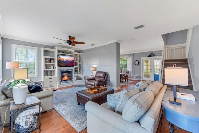 living room with plenty of natural light, light hardwood / wood-style flooring, and crown molding