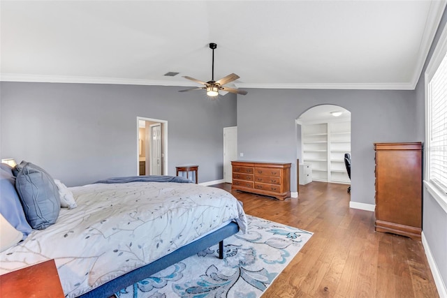 bedroom with a spacious closet, wood-type flooring, ornamental molding, and ceiling fan