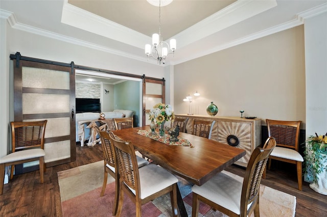 dining area featuring an inviting chandelier, dark hardwood / wood-style floors, a tray ceiling, crown molding, and a barn door