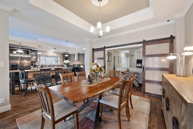 dining space featuring a tray ceiling, dark hardwood / wood-style floors, ornamental molding, and a barn door