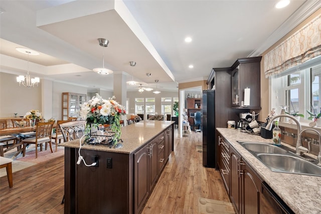 kitchen featuring pendant lighting, black appliances, a kitchen island, sink, and dark brown cabinetry