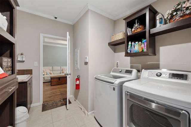 clothes washing area with washing machine and dryer, light tile patterned flooring, and ornamental molding