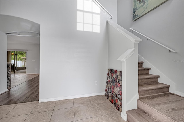 staircase featuring a high ceiling and tile patterned floors