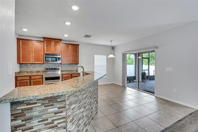 kitchen with appliances with stainless steel finishes, tasteful backsplash, hanging light fixtures, light stone counters, and light tile patterned flooring