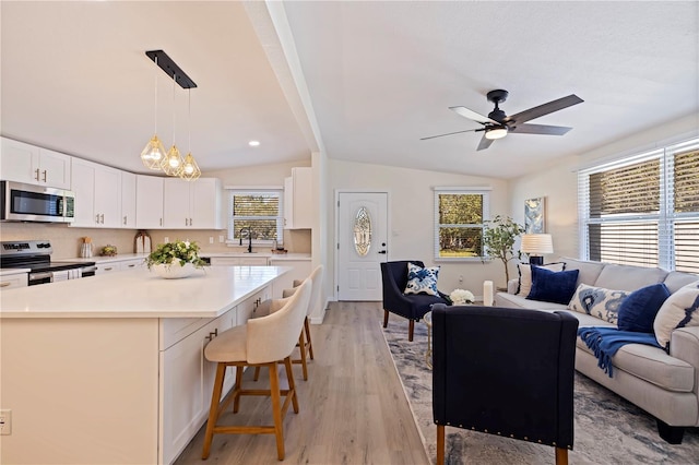 kitchen featuring open floor plan, light countertops, appliances with stainless steel finishes, a center island, and pendant lighting