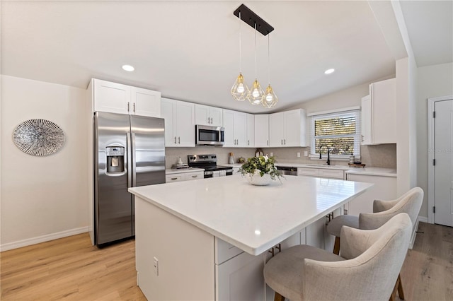 kitchen featuring stainless steel appliances, light countertops, white cabinetry, and a center island