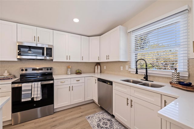 kitchen with tasteful backsplash, white cabinets, appliances with stainless steel finishes, light countertops, and a sink