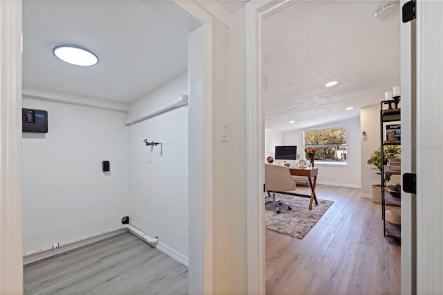 washroom featuring light wood-style flooring, baseboards, and a textured ceiling