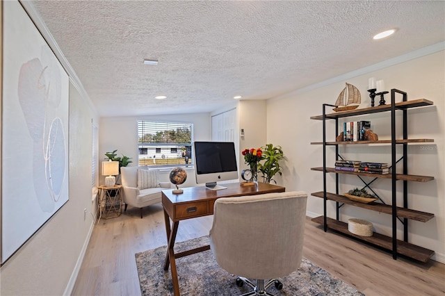 home office featuring crown molding, light wood finished floors, a textured ceiling, and baseboards