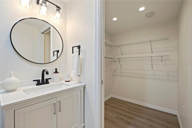 bathroom featuring recessed lighting, wood finished floors, vanity, and baseboards