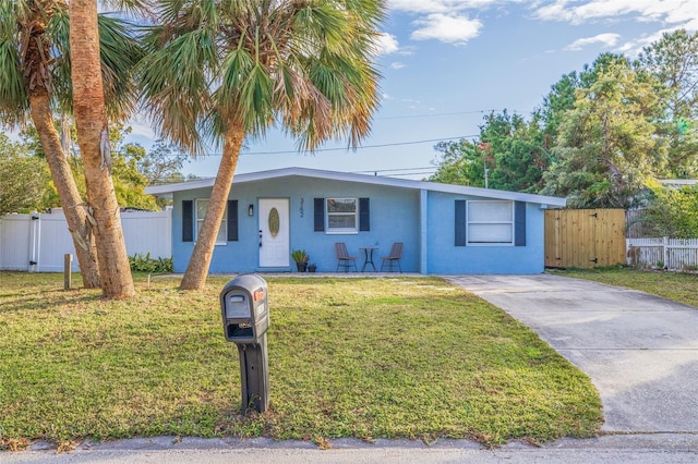 ranch-style house with concrete driveway, a front lawn, fence, and stucco siding