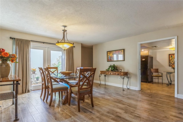 dining space featuring wood-type flooring and a textured ceiling