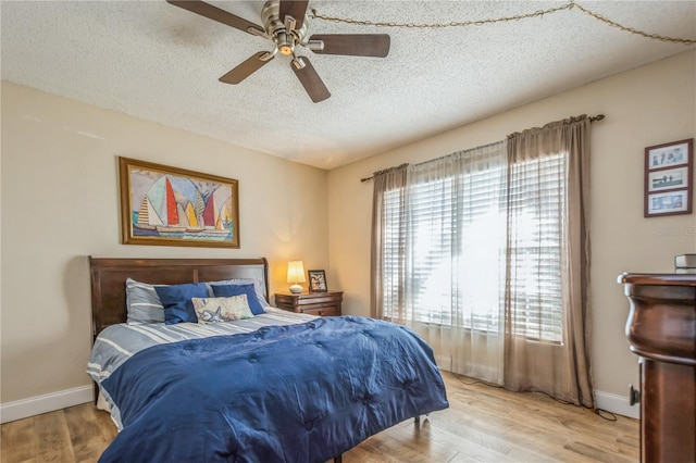 bedroom with light wood-type flooring, ceiling fan, and a textured ceiling