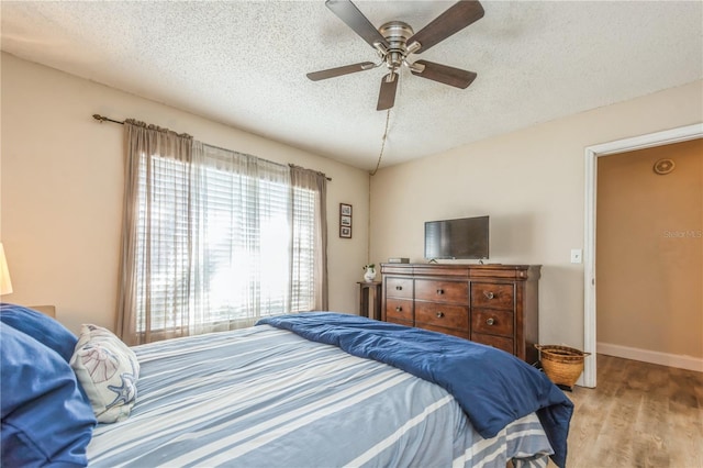 bedroom featuring ceiling fan, a textured ceiling, and wood-type flooring