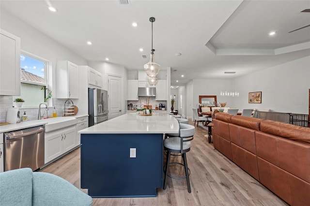 kitchen with sink, decorative light fixtures, appliances with stainless steel finishes, a kitchen island, and white cabinets