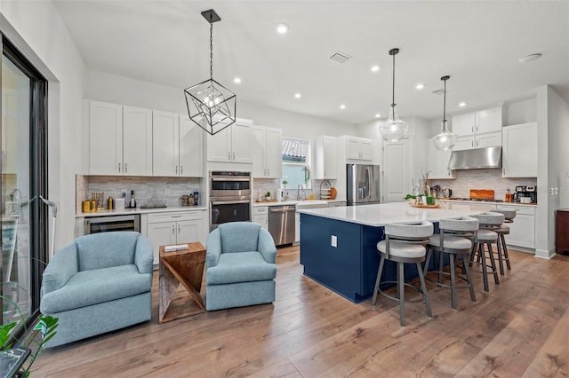 kitchen featuring stainless steel appliances, white cabinetry, a kitchen island, and pendant lighting