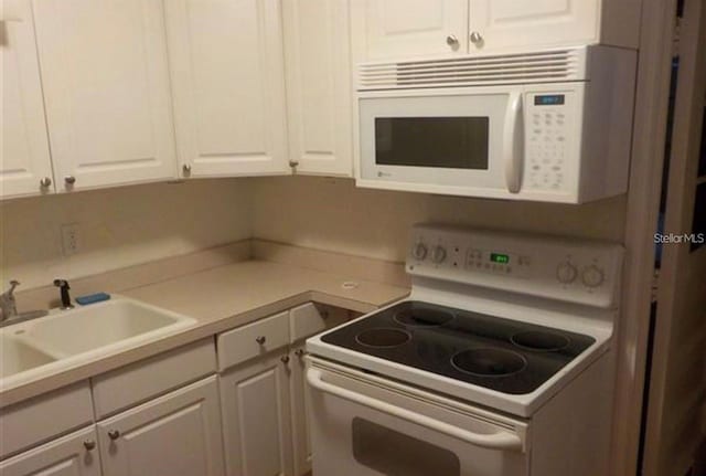 kitchen featuring sink, white cabinets, and white appliances