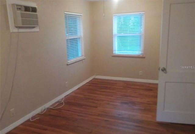 spare room featuring a wall mounted AC and dark hardwood / wood-style floors