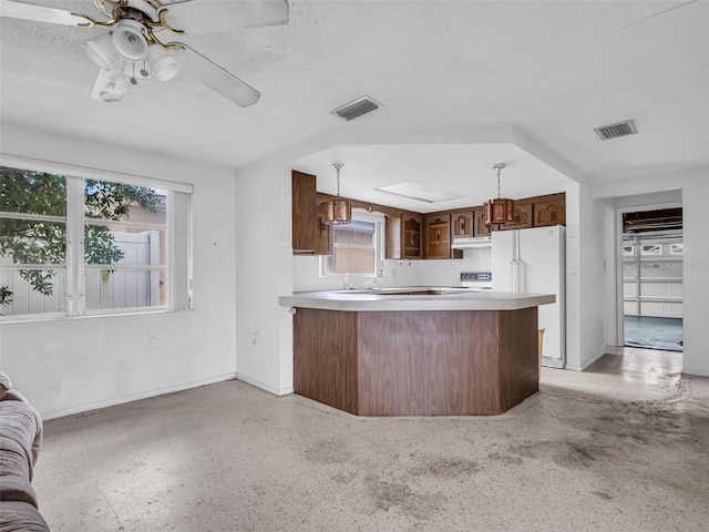 kitchen with white refrigerator, ceiling fan, kitchen peninsula, and hanging light fixtures