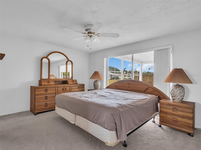 bedroom featuring a textured ceiling, light colored carpet, and ceiling fan