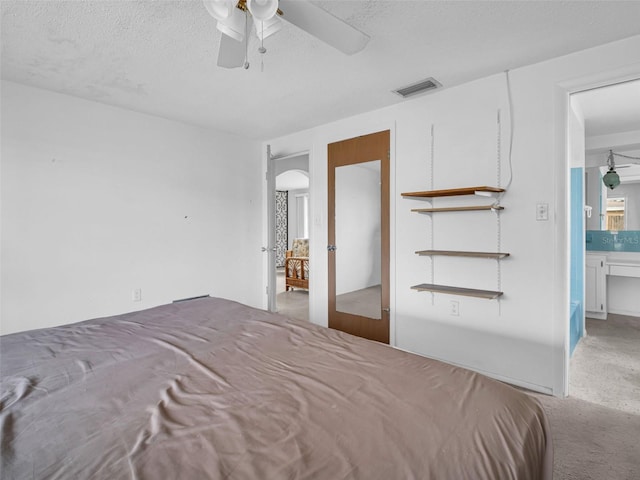 unfurnished bedroom featuring french doors, ensuite bathroom, a textured ceiling, carpet flooring, and ceiling fan