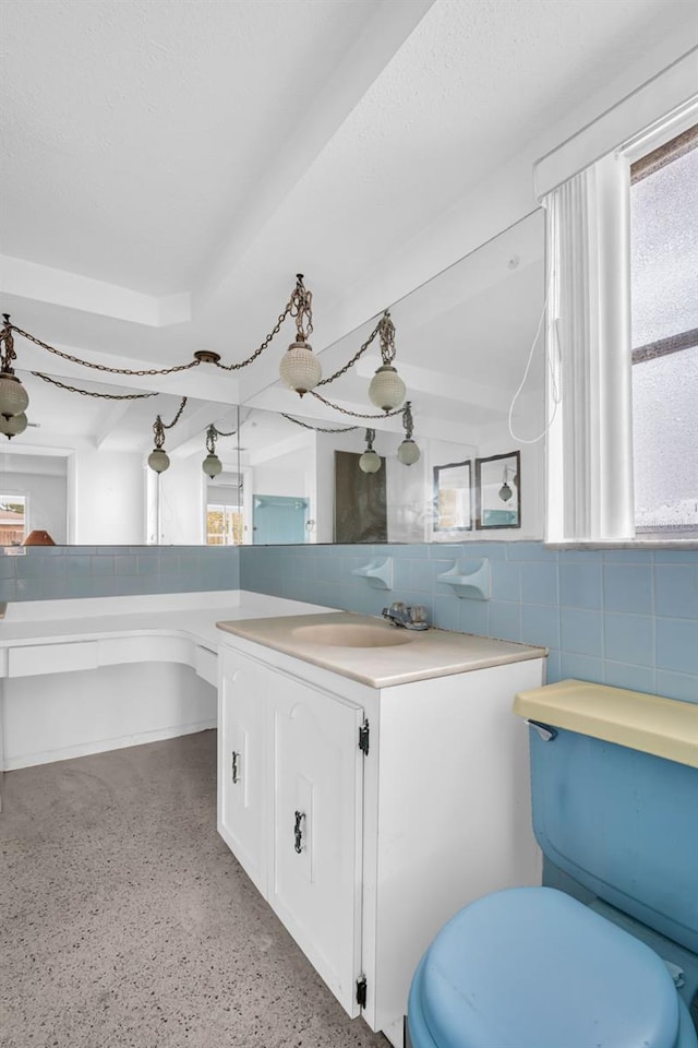 bathroom with tile walls, backsplash, beam ceiling, vanity, and toilet