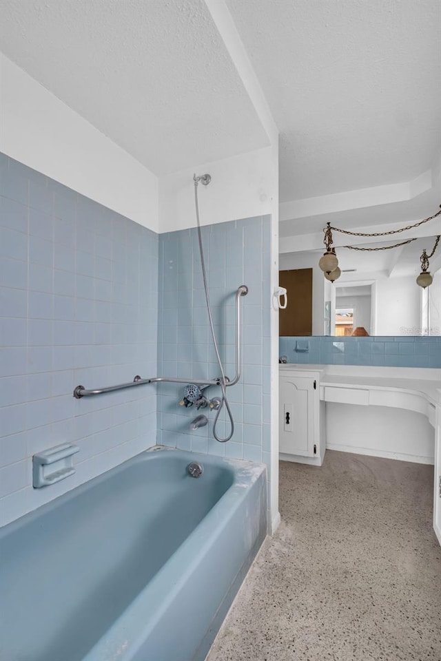 bathroom featuring tiled shower / bath, vanity, and a textured ceiling