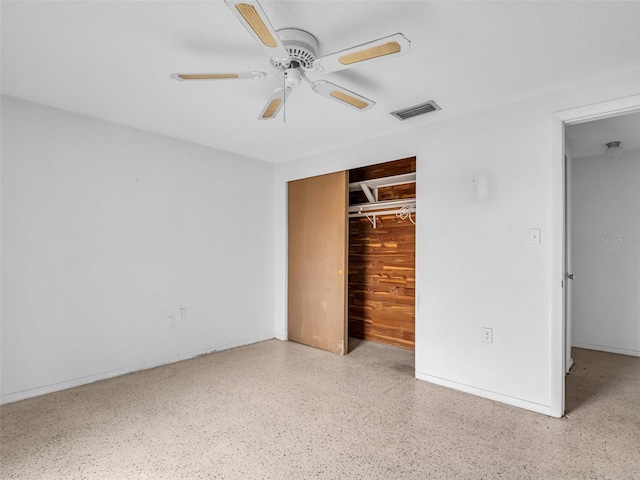 unfurnished bedroom featuring a closet, ceiling fan, and wood walls