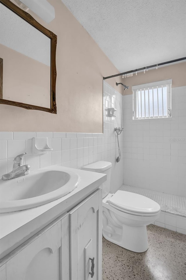 bathroom featuring tiled shower, tile walls, a textured ceiling, and toilet