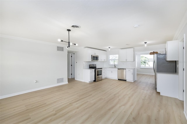 kitchen featuring appliances with stainless steel finishes, decorative backsplash, white cabinets, ornamental molding, and light hardwood / wood-style flooring