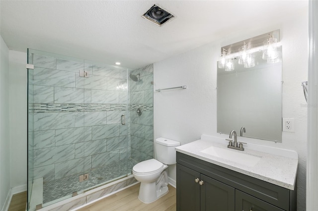 bathroom featuring a textured ceiling, an enclosed shower, vanity, toilet, and hardwood / wood-style flooring