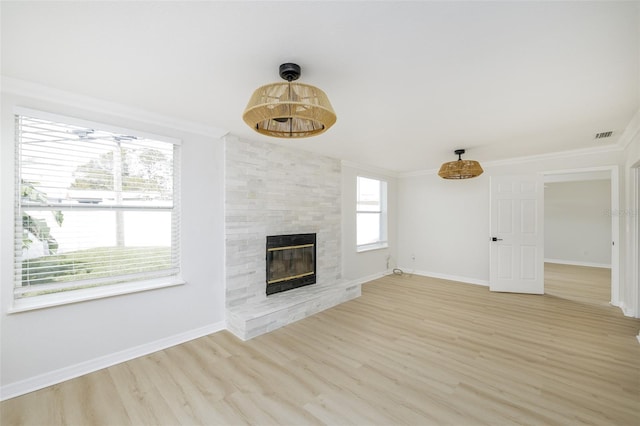 unfurnished living room featuring ornamental molding, light hardwood / wood-style floors, and a stone fireplace