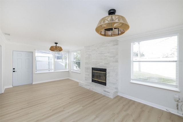 unfurnished living room with light wood-type flooring, a fireplace, and ornamental molding