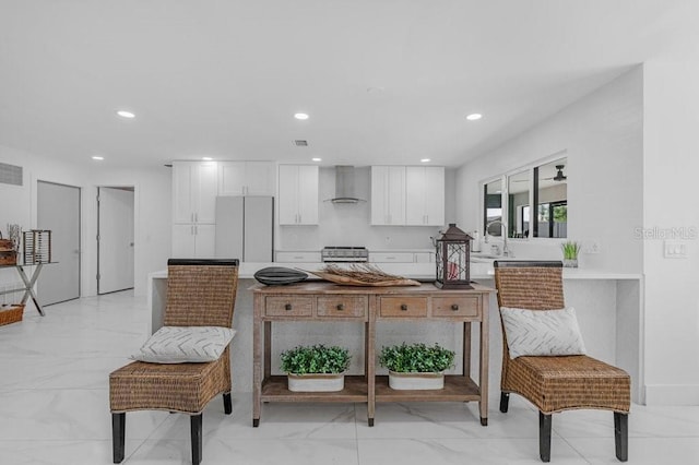 kitchen featuring white fridge, white cabinetry, wall chimney range hood, stainless steel stove, and sink