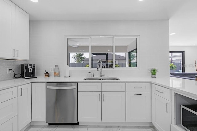 kitchen featuring white cabinetry, stainless steel dishwasher, tasteful backsplash, and sink