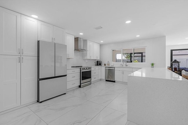 kitchen featuring white cabinetry, kitchen peninsula, stainless steel appliances, and wall chimney exhaust hood