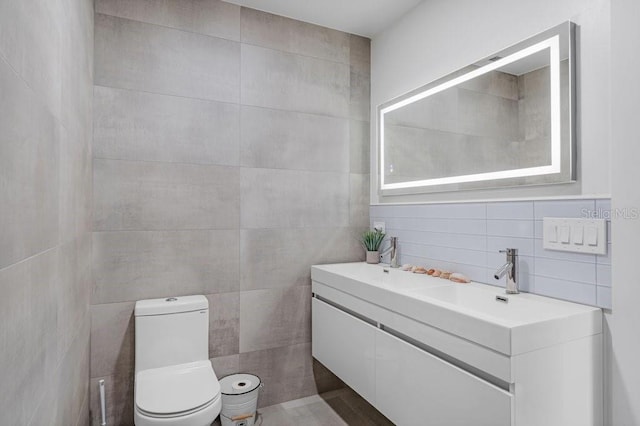 bathroom with toilet, tile walls, and vanity